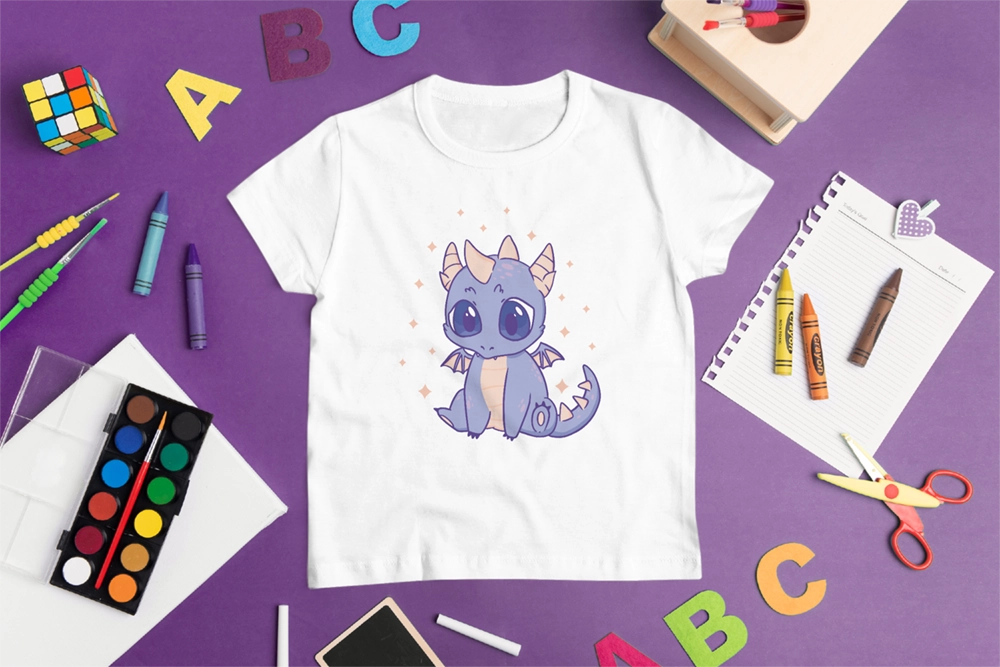 Weißes Kinder T-Shirt mit niedlichem lila Drachen-Bügelbild im Cartoon-Stil, dekoriert mit Schulmaterialien wie Wachsmalstiften, Wasserfarben, Schere und Buchstaben auf lila Hintergrund